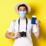 concept-covid-19-travelling-quarantine-happy-man-tourist-with-camera-showing-passport-tickets-vacation-going-trip-during-pandemic-yellow-background_cambodia